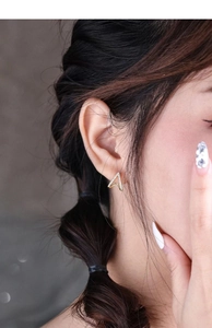 Close-up of a s925 silver V-shaped stud earring with gold plating and white zircons