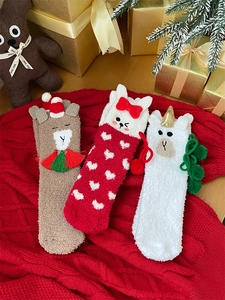 Detail of plush coral fleece Christmas socks featuring cartoon reindeer and alpaca designs