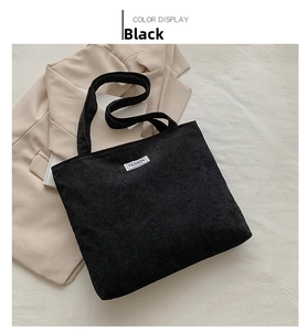 Detail of black corduroy tote bag featuring vertical texture and a fashion label