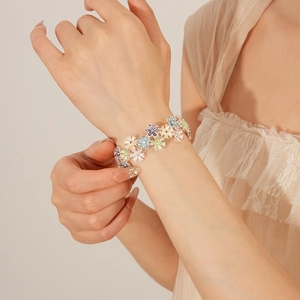 Close-up of colorful enamel flower bracelet on wrist with purple and yellow petals