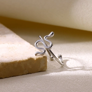 Détail macro d'une bague serpent argentée avec finition polie sur support pierre