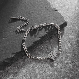 Silver Figaro chain bracelet with Celtic knot pendant on minimalist stone surface