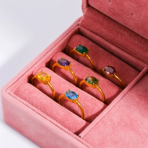 Detail of six gold-plated stainless steel rings with colorful oval birthstones in a pink box