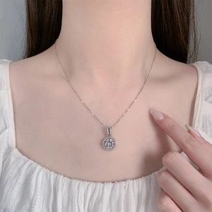 Close-up of 2 carat round zircon pendant necklace with pavé stones on a model's neck
