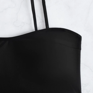 Haut de bikini noir minimaliste à fines bretelles sur fond de marbre blanc