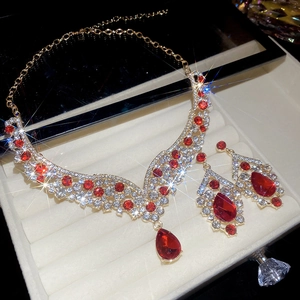 Macro shot of red teardrop gems and rhinestones on gold jewelry set in velvet box
