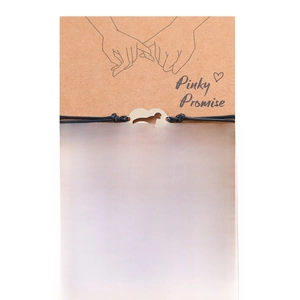 Detail of pinky promise card with black heart dinosaur and red dinosaur woven bracelets