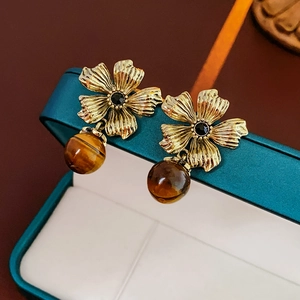 Vue macro de boucles d'oreilles fleurs dorées vintage avec perles oeil de tigre