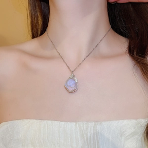 Close-up of a silver necklace with a wire-wrapped purple irregular stone pendant
