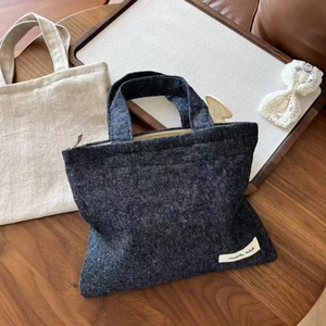 Detail of mini denim and linen tote bags with zippers and simple wish woven labels