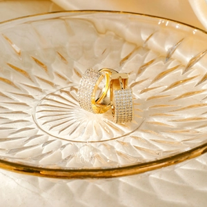 Luxury gold-plated huggie hoop earrings with micro-paved cubic zirconia on satin background