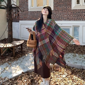 Bohemian style knitted shawl with wavy patterns and tassels, shown in an outdoor setting