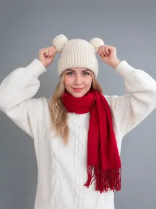 Detail of white knit beanie with bear ears and red fringe scarf on a model for winter