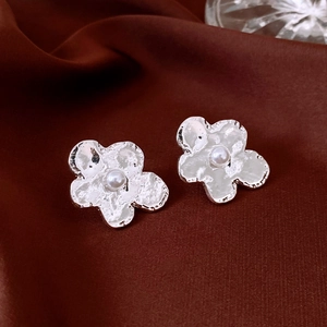 Macro view of silver flower earrings with irregular petals and a white center pearl
