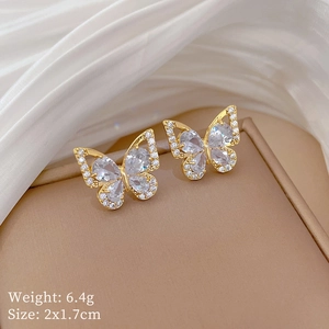 Detail of gold butterfly stud earrings with sparkling white zircons on a jewelry box