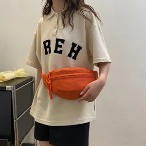Detail view of bright orange crossbody chest bag featuring heavy-duty zippers and nylon fabric