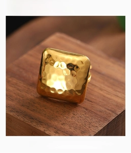Detail view of gold square textured earrings with anti-oxidation finish on wood