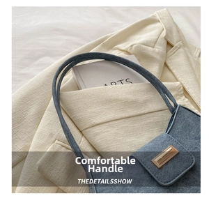 Close-up of blue denim texture handbag with golden metal buckle on ivory blazer background