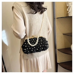 Détail du sac dentelle noir avec texture florale et bandoulière en perles élégante