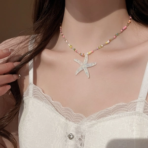 Detailed view of colorful beaded necklace with iridescent starfish pendant on a model