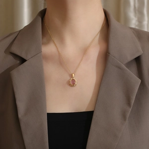Close-up of pink cat eye stone necklace with gold relief pendant on model's neck