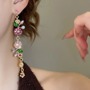 Detail von langen floralen Quastenohrringen mit bunten Strasssteinen am Frauenohr