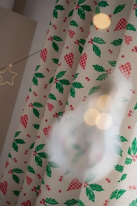 Detail of cotton linen curtain with green leaves and red heart patterns in warm lighting