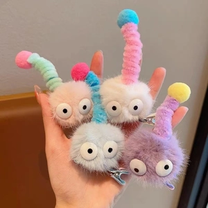 Détail de quatre barrettes chenilles en peluche colorées avec de mignons yeux de dessin animé