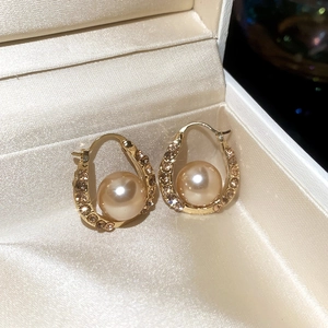 Close-up of champagne gold hoop earrings with sparkling rhinestones and a central pearl