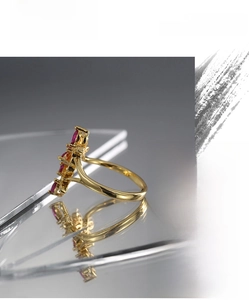 Detail of gold butterfly ring with red zircon stones on a reflective mirror background