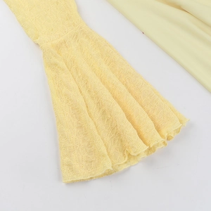 Close-up of yellow lace fabric detailing the flared sleeve cuffs on this elegant dress