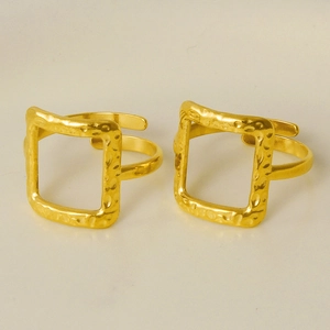 Detail view of two gold stainless steel open rings with square hollows and hammered texture