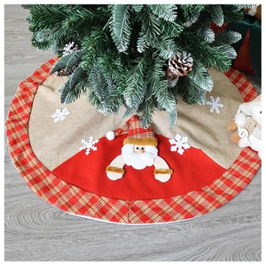 Detail of Christmas tree skirt with Santa Claus applique and plaid edge on wood floor