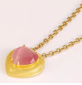 Macro shot of pink heart gemstone necklace with vintage style golden beaded frame