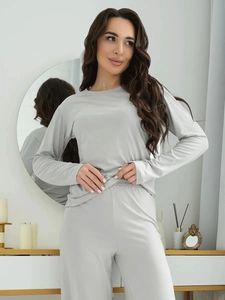 Detail of light gray long-sleeve loungewear set in a cozy home interior setting