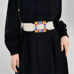Detail of white wide elastic waist belt with a gold square buckle and colorful gemstones