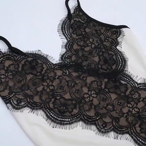 Close-up of delicate black floral lace V-neckline and white satin on a summer dress