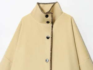 Detailed view of yellow wool coat featuring standing collar and dark contrast stitching
