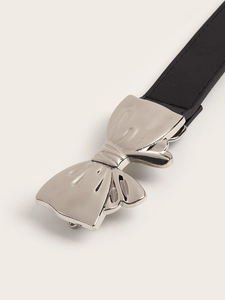 Detail of a polished silver bow buckle on a slim black leather belt with a macro view