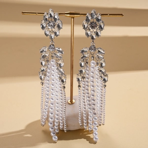 Détail de boucles d'oreilles à pompon avec perles et cristaux sur support doré