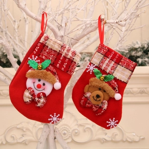 Red felt Christmas stockings with snowman and bear designs hanging on a festive branch