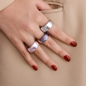 Close-up of stacked titanium steel rings with faceted purple and pink gemstones