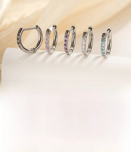 Close-up of 8mm and 10mm titanium huggie hoop earrings with multi-colored zircon stones