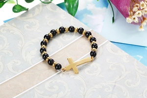 Vue détaillée d'un bracelet de perles avec croix dorée sur un coffret cadeau élégant