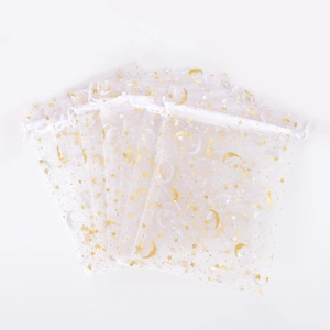 Close-up of white organza drawstring pouches with gold star and moon patterns
