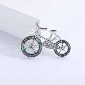 Elegant silver bicycle brooch with abalone shell wheels and white faux pearl detail
