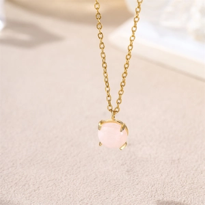 Macro shot of 18k gold necklace featuring a round pink gemstone in a four-prong setting