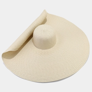 Dettaglio ravvicinato della trama di paglia e della tesa larga ondulata di questo cappello beige