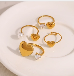 Detailed top view of gold heart rings with pearls and zircon on a ceramic tray