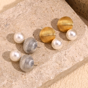 Macro detail of gold and silver balloon stud earrings with pearls on stone background